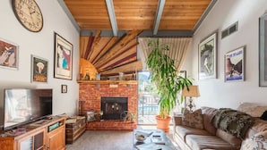 A cozy living room with a brick fireplace, a television, and a comfortable sofa.