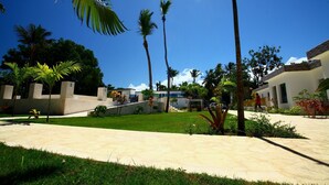A modern house with a spacious patio, palm trees, and a clear blue sky. - Pueblo Checo - Czech Guest-House (Cabarete)