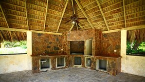A stone-walled room with a thatched roof and a ceiling fan. - Pueblo Checo - Czech Guest-House (Cabarete)