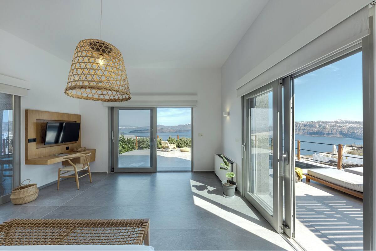A modern bedroom with a TV, desk, and large sliding glass doors to a balcony with a view.