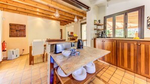 Une cuisine avec des meubles en bois, un plan de travail en granit et une cuisinière encastrée. Une fenêtre offre une vue sur la verdure à l’extérieur.