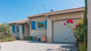 A two-story house with a tiled roof, a garage, and a garden with potted plants and flowers. - Lovely house near the historical center of Narbonne and main shops, private pool (Narbonne)
