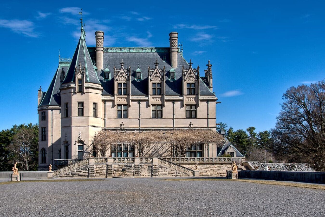 A large, historic building with a prominent tower, multiple chimneys, and a grand entrance with steps.