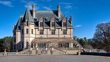 A large, historic building with a prominent tower, multiple chimneys, and a grand entrance with steps.