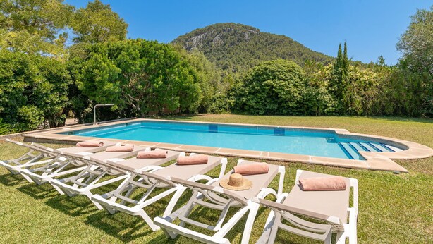 A swimming pool with lounge chairs and a mountain backdrop.