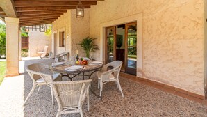 An outdoor patio with wicker furniture, a round table, and a bottle of champagne.