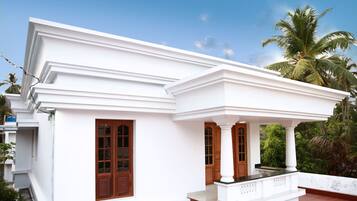 A white building with a covered porch, wooden doors, and a tiled roof.