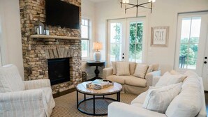 A living room with a stone fireplace, a round coffee table, and a beige sofa. - Luxury Cottage in the Heart of North Georgia (Dahlonega)