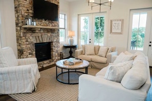 A living room with a stone fireplace, a round coffee table, and a beige sofa. - Luxury Cottage in the Heart of North Georgia (Dahlonega)