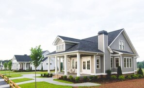 A residential house with a covered porch, a driveway, and a well-maintained lawn.