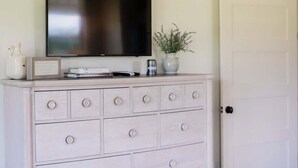 A white dresser with a flat-screen TV mounted above it, a small vase with a plant, and a few decorative items. - Luxury Cottage in the Heart of North Georgia (Dahlonega)