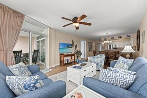 A living room with a ceiling fan, a TV, and a dining area with a table and chairs.