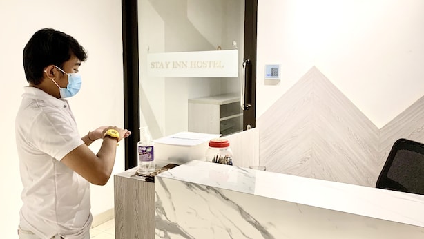 A reception desk at Stay Inn Hostel with a marble top, a hand sanitizer dispenser, and a small jar with a red lid. - Stay Inn Hostel Jakarta - Adults only (Jakarta)