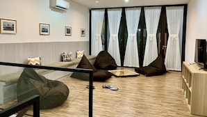 A modern living room with a glass railing, a sofa set, bean bags, a flat-screen TV, and a wooden floor. - Stay Inn Hostel Jakarta - Adults only (Jakarta)