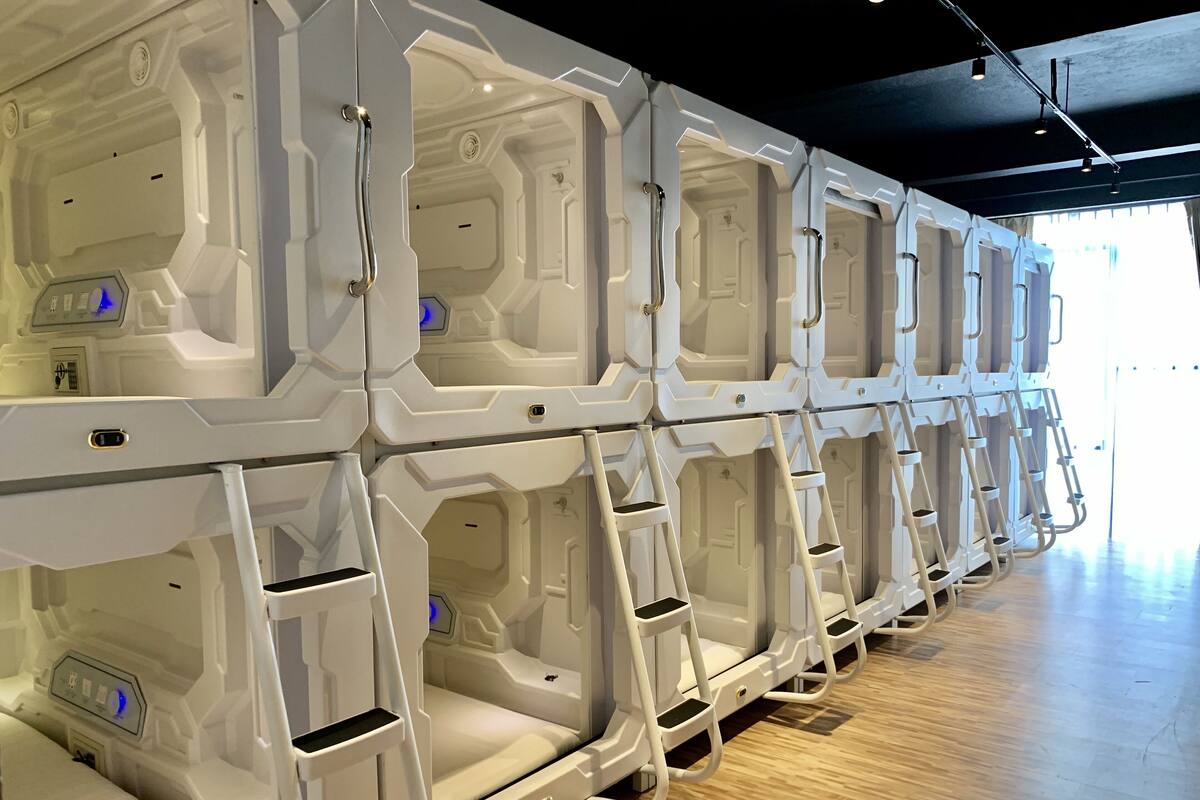 Een rij stapelbedden met ingebouwde ladders en opbergvakken, in een moderne hotelkamer.