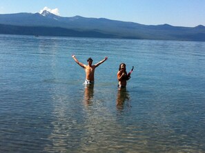 Duas pessoas num lago, com montanhas ao fundo.