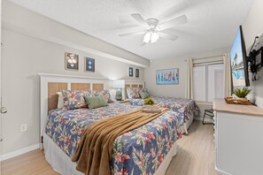 Un dormitorio con cama, ventilador de techo y ventana con persianas.