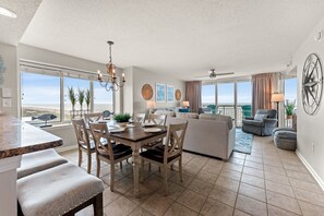 A spacious living area with a dining table, seating, and a view of the ocean.