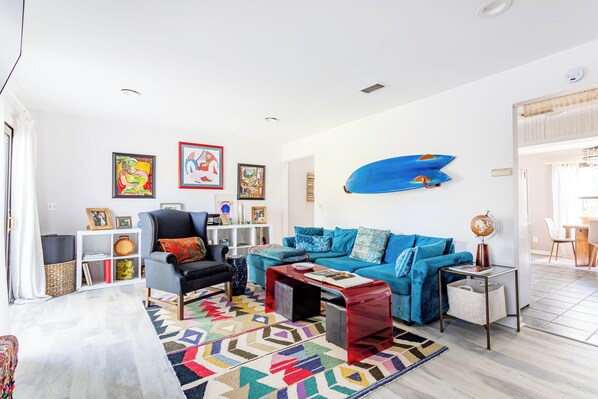 A living room with a blue sofa, a black armchair, a coffee table, and a colorful rug.