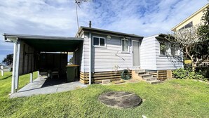 A single-story house with a garage, a small porch, and a grassy yard. - Sand N Salt - spectacular views (Minnie Water)
