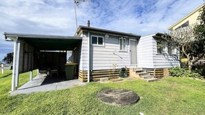 Ein eingeschossiges Haus mit Garage, einer kleinen Veranda und einem Rasen.