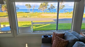 Ein Zimmer mit großem Fenster mit Blick auf einen Golfplatz und das Meer.