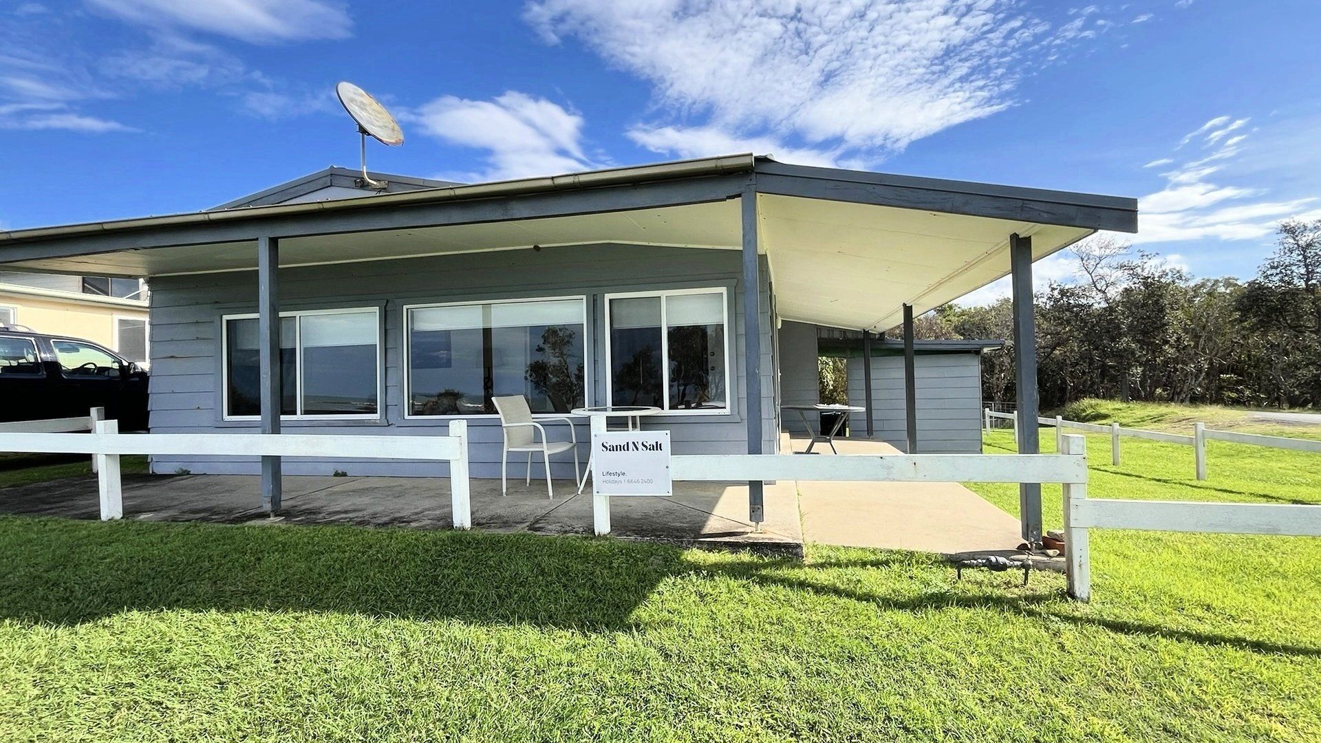 A modern building with a covered patio area, large windows, and a sign indicating 'Sand N Salt Lifestyle.'