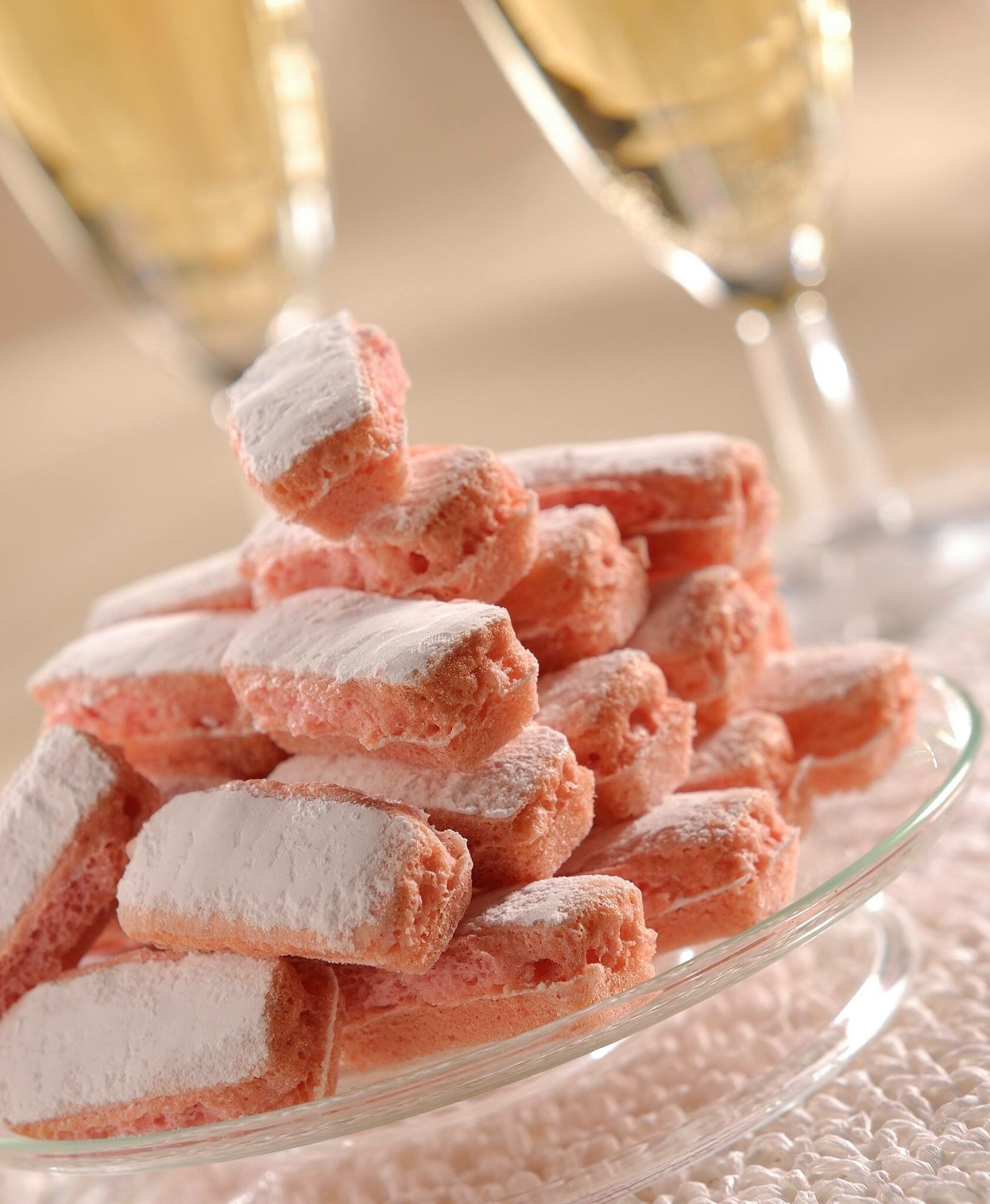 A glass plate filled with pink, powdered-covered pastries.