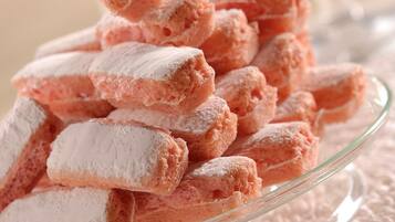 A glass plate filled with pink, powdered-covered pastries.