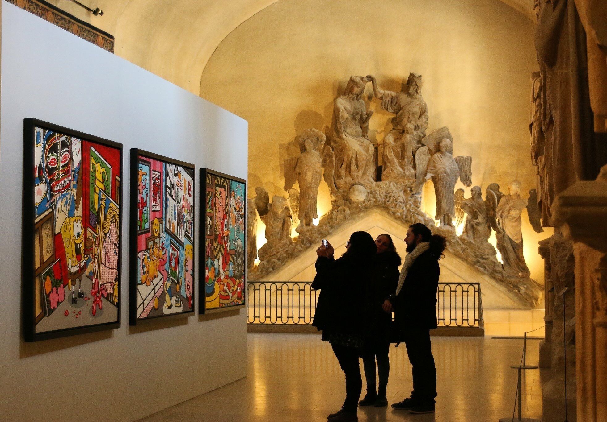 A gallery with classical sculptures and colorful paintings.