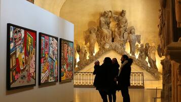 A gallery with classical sculptures and colorful paintings.
