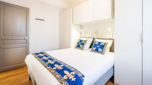 Une chambre à coucher avec un lit, des murs blancs, une porte en bois et une armoire.