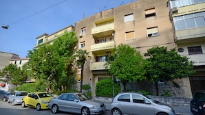 A row of parked cars along a street with a multi-story building featuring balconies and air conditioning units. - Split Center Beautiful Apartment (Split)