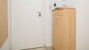 A room with a white door, a wooden cabinet with drawers, a framed picture on the wall, and a ceiling light. - Split Center Beautiful Apartment (Split)