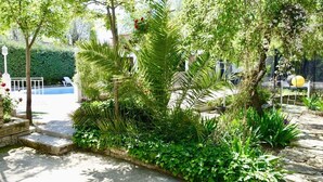 A garden with a pool, stone steps, and various plants. - Villa with private pool, large garden and leisure activities, 20 min from Madrid (Navalcarnero)