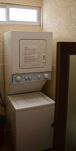 Una lavadora blanca y compacta con un panel de control y un manual de instrucciones de papel encima.