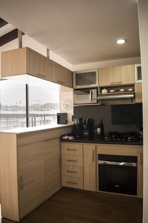 Una cocina moderna con armarios de madera, un microondas, una estufa y un reloj.