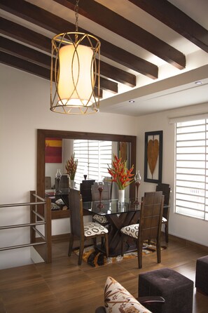 Un comedor con una mesa de vidrio, sillas y una lámpara colgante.
