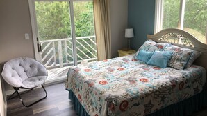 A bedroom with a bed, a chair, a nightstand, and a window with curtains.