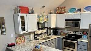 A modern kitchen with white cabinets, a central island, stainless steel appliances, and decorative items.