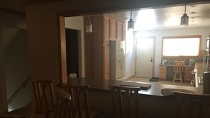 A kitchen with wooden cabinets, a refrigerator, a sink, and a window. - Luxurious Lodging in the Wind River Canyon (Thermopolis)