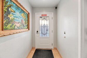 En hall med en vit dörr som har en panel av frostat glas och en skylt ovanför.