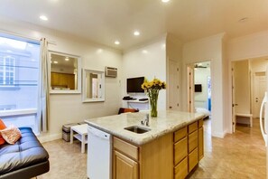 A modern kitchen with a central island, a built-in dishwasher, and a window overlooking the city.
