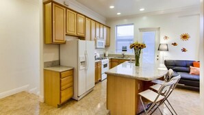 Una cocina moderna con armarios de madera, una isla central y un comedor con sillas.