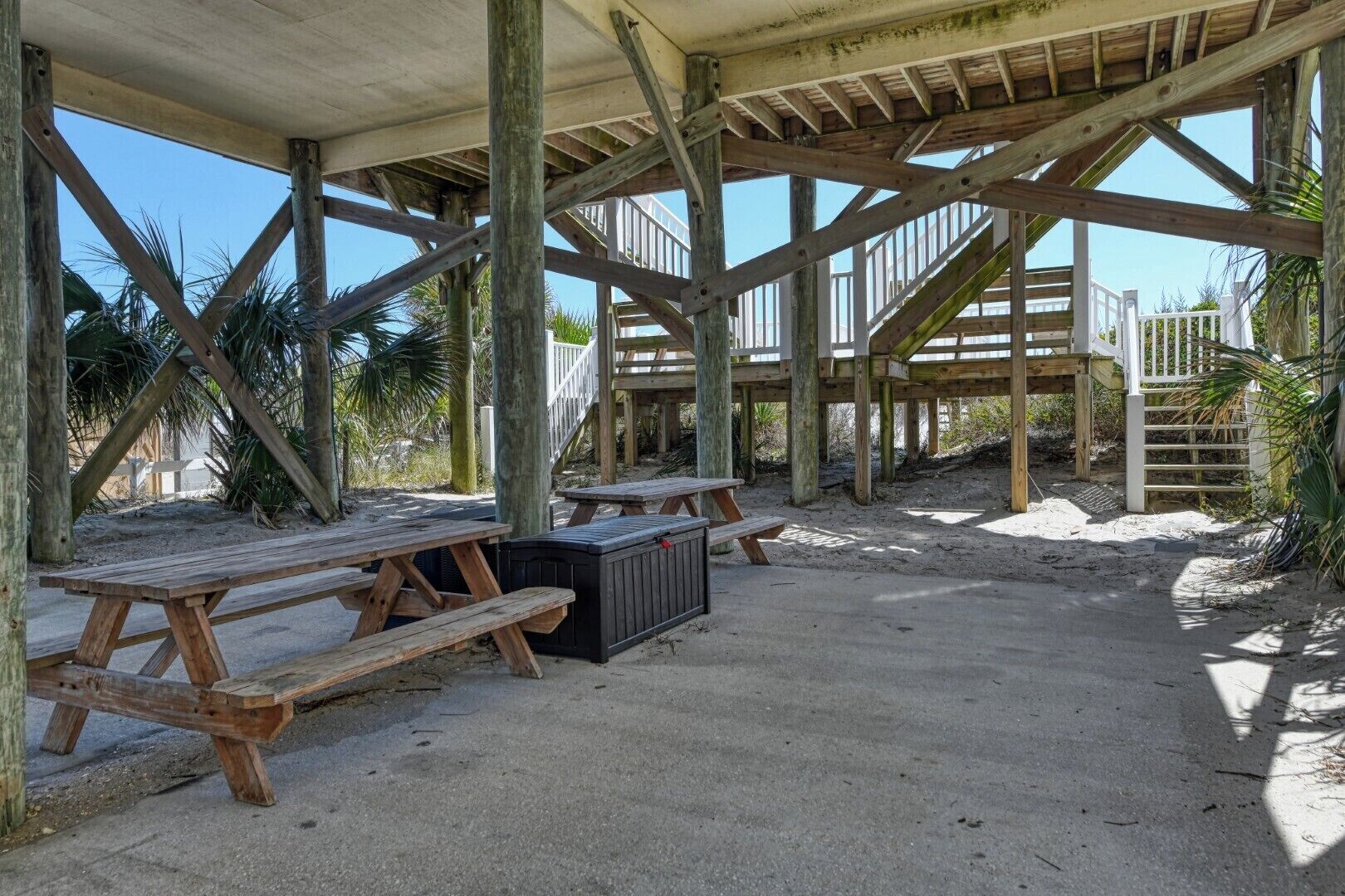 Eine Holzterrasse mit Picknicktischen und einem überdachten Sitzbereich.