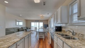 A kitchen with granite countertops, a dining area with a table and chairs, and a view of the ocean through large windows. - Against The Wind Side B, Oceanfront Home, Awesome view of Garden City Pier (Garden City Beach)