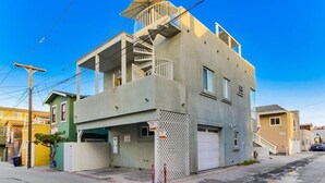 Edificio de dos plantas con garaje, una escalera visible y un área cercada.