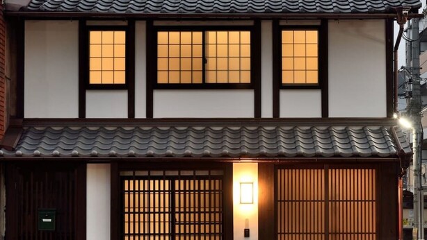 A traditional Japanese building with a tiled roof, wooden sliding doors, and a small porch area. - Machiya Kamo 7 (Kyoto)