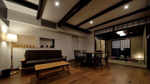A traditional Japanese-style living room with a sofa, dining table, and chairs. - Machiya Kamo 7 (Kyoto)