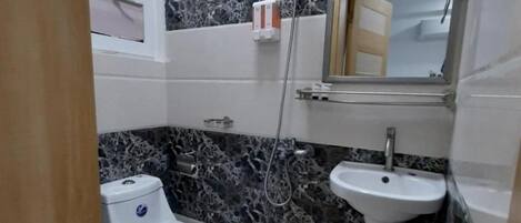 A bathroom with a toilet, sink, and shower.